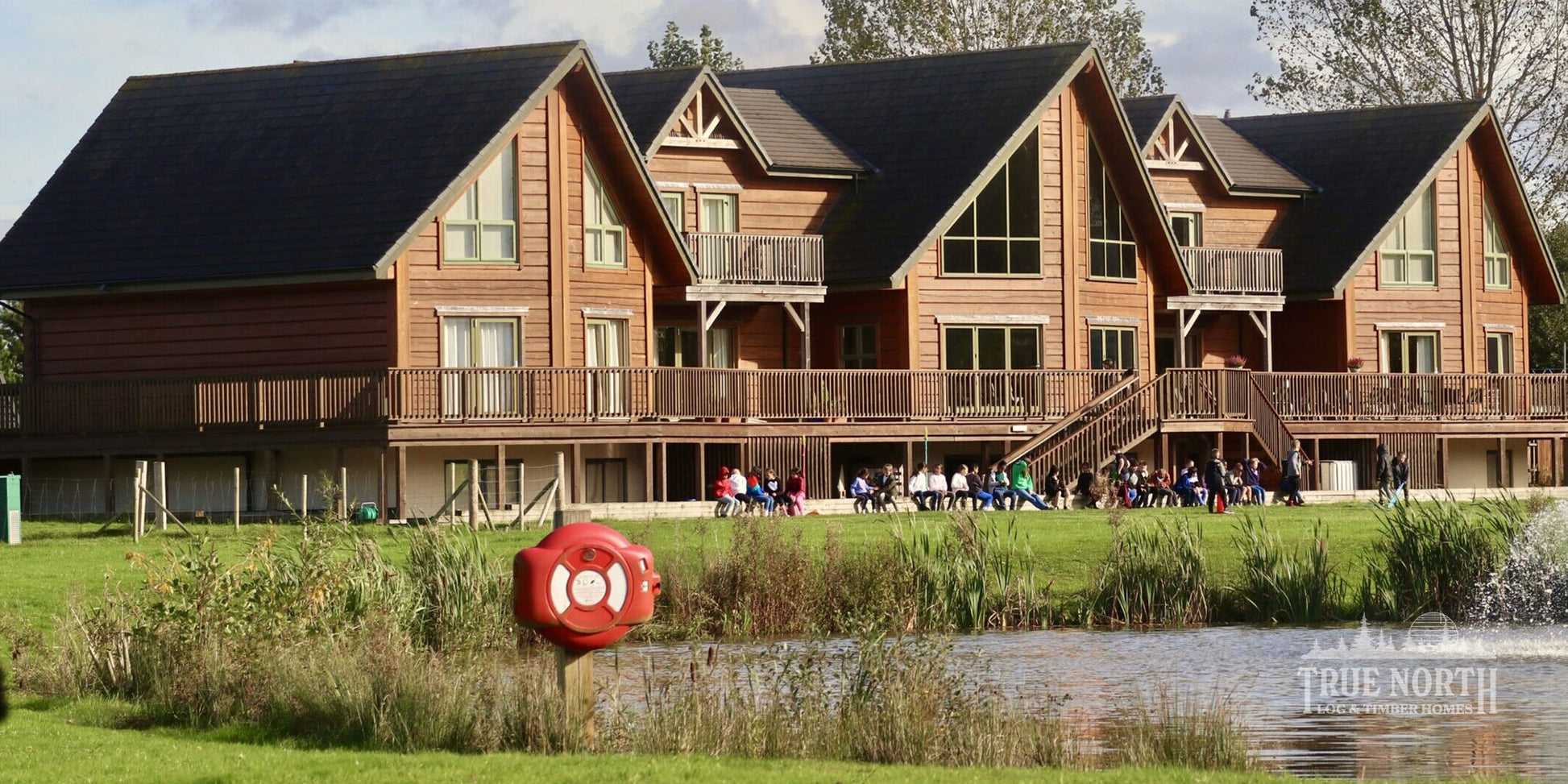 Alaskan commercial Canadian log building built for Foundation Matters charity - Front with youth group enjoying the gardens